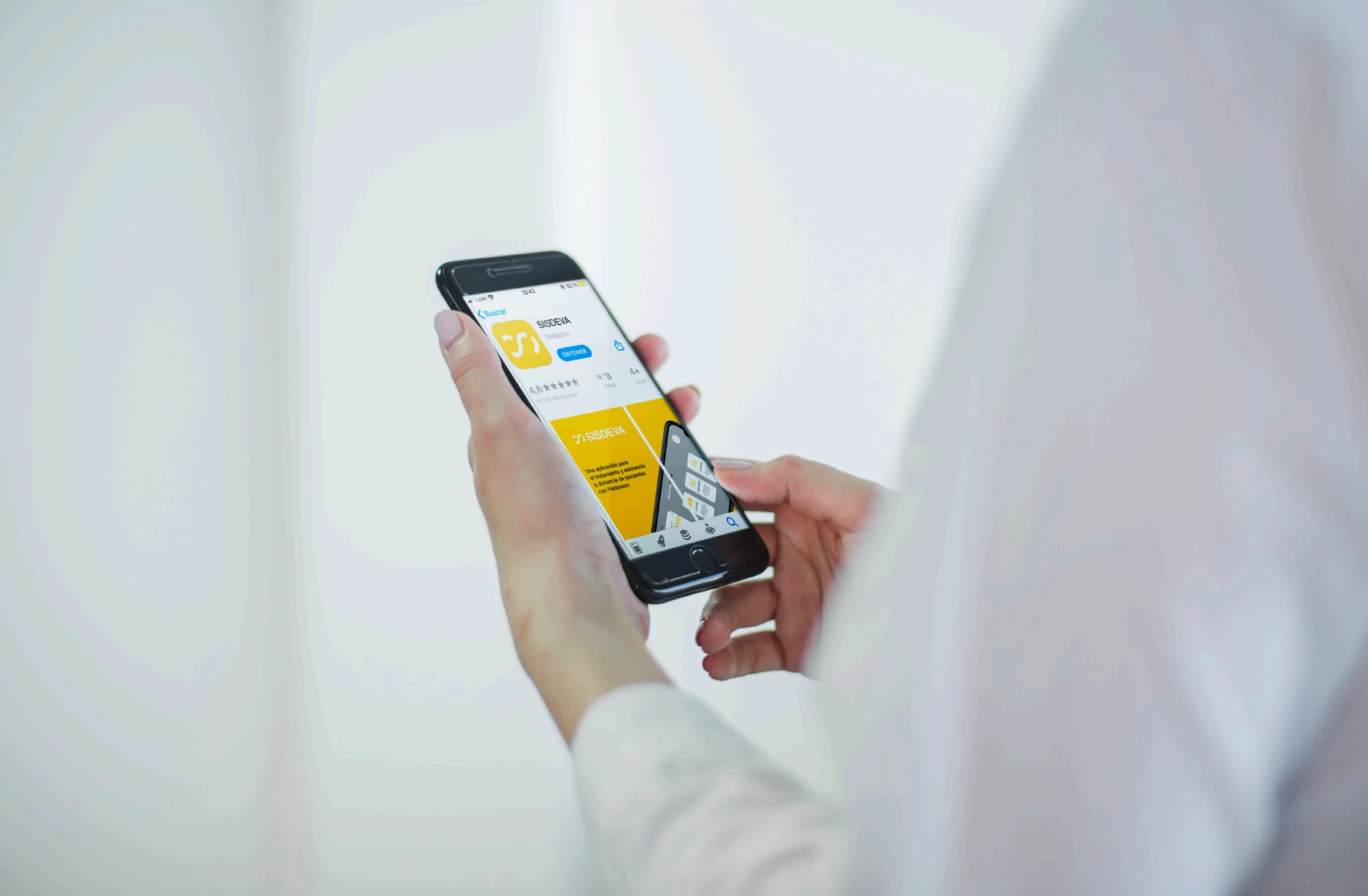 Mockup de una persona sujetando un móvil con la ficha de SISDEVA abierta en la App Store