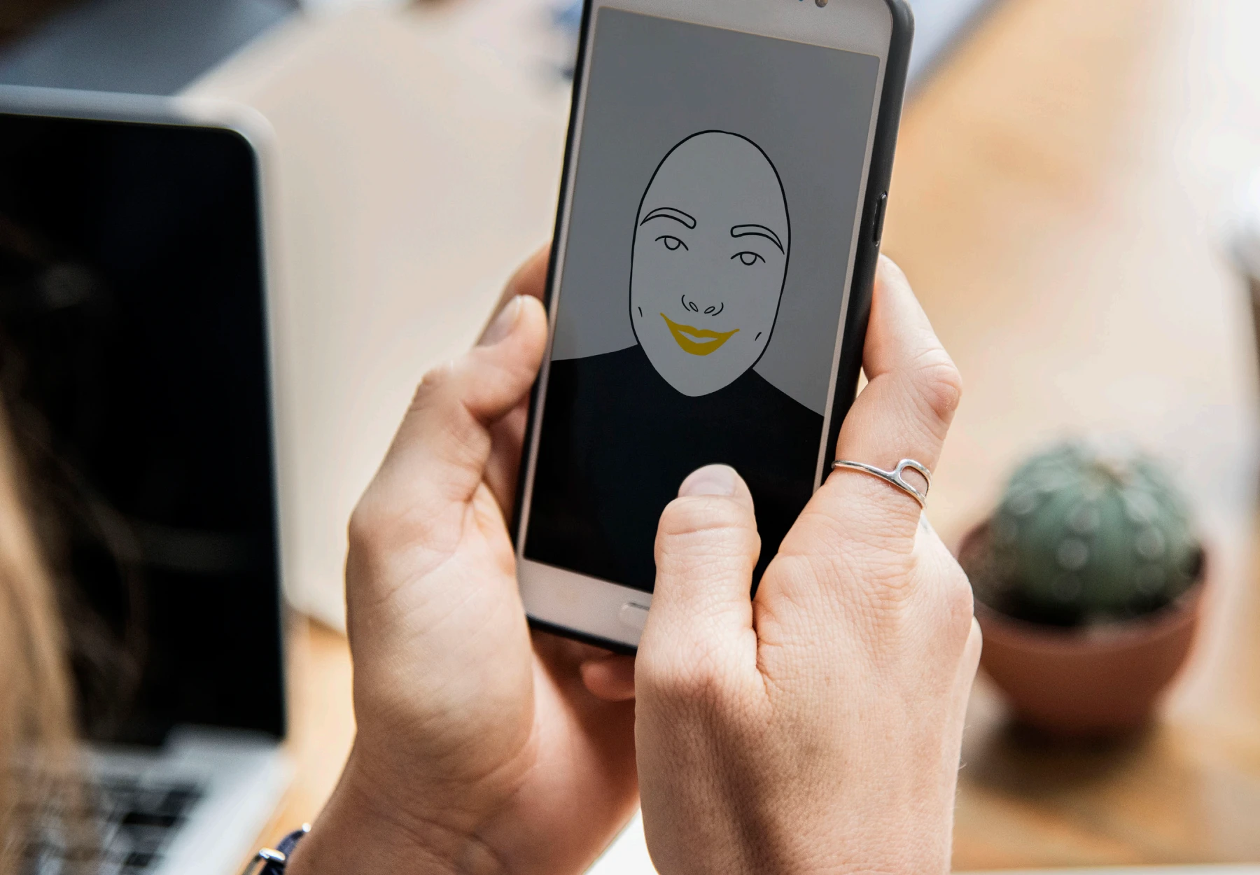 Persona sujetando un móvil con una ilustración de un rostro en pantalla