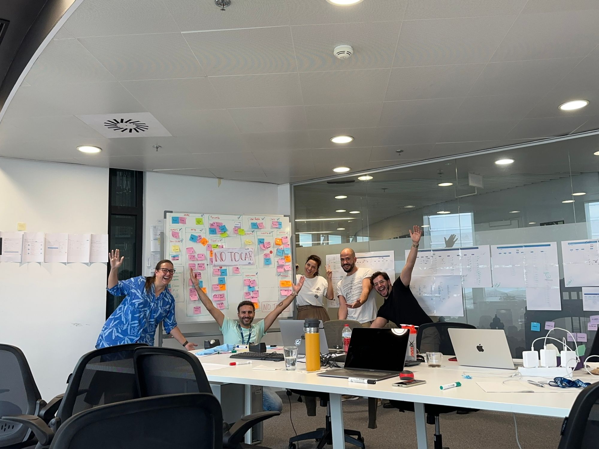 Equipo de producto celebrando frente al whiteboard con la arquitectura de la información del workshop